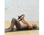 Femme allongée sur un tapis de gym avec un Pilates Circle 36 cm